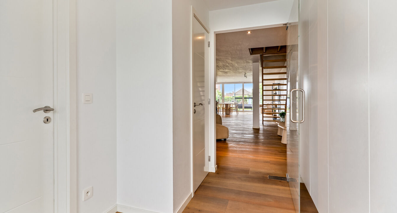 Bij het betreden van de woning wordt u verwelkomd in een verzorgde inkomhal met vestiaire en gastentoilet, die meteen de hoogwaardige afwerking van de woning weerspiegelt. Het gelijkvloers werd doordacht ingericht met een praktische bureauruimte, ideaal v