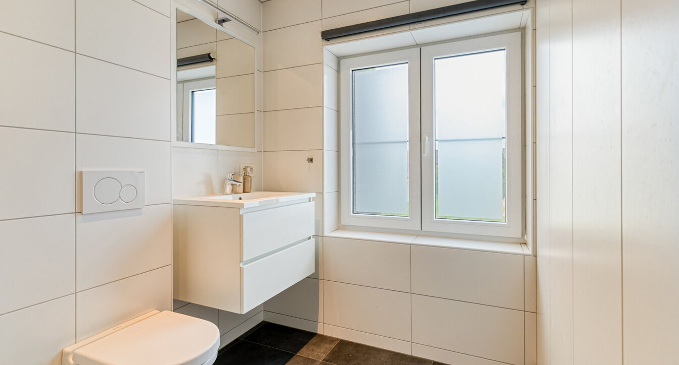 Bij het betreden van de woning wordt u verwelkomd in een verzorgde inkomhal met vestiaire en gastentoilet, die meteen de hoogwaardige afwerking van de woning weerspiegelt. Het gelijkvloers werd doordacht ingericht met een praktische bureauruimte, ideaal v