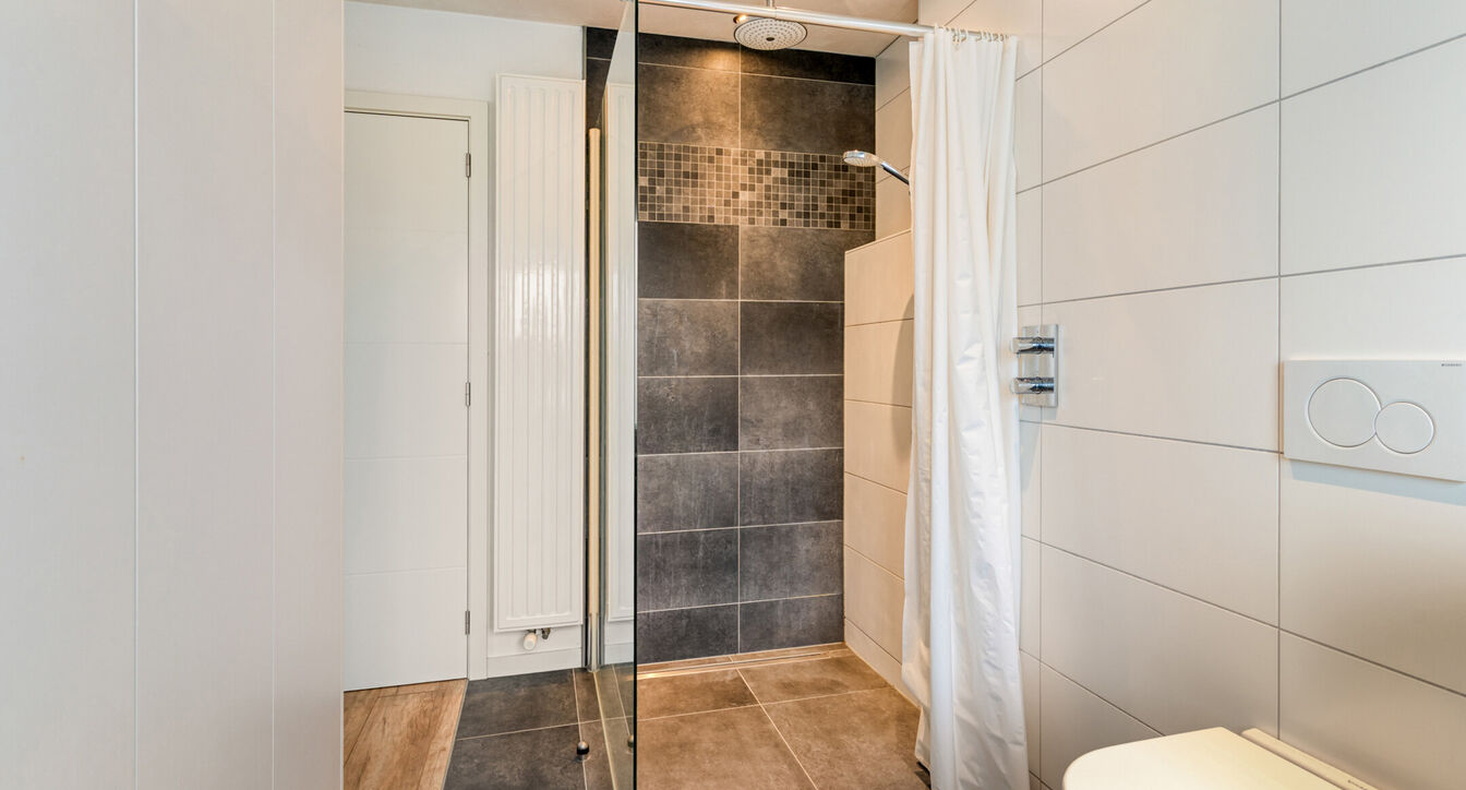 Bij het betreden van de woning wordt u verwelkomd in een verzorgde inkomhal met vestiaire en gastentoilet, die meteen de hoogwaardige afwerking van de woning weerspiegelt. Het gelijkvloers werd doordacht ingericht met een praktische bureauruimte, ideaal v